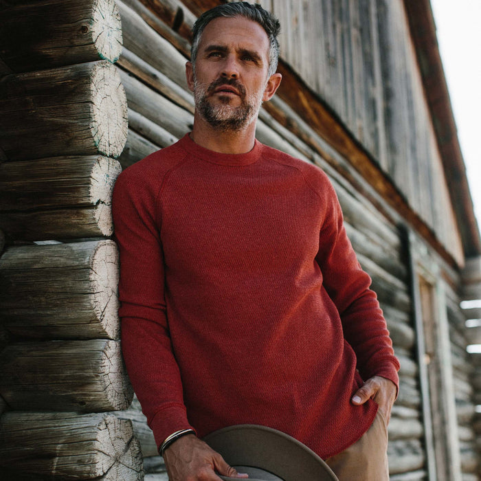 fit model next to a cabin in The Heavy Bag Waffle Crewneck in Engine