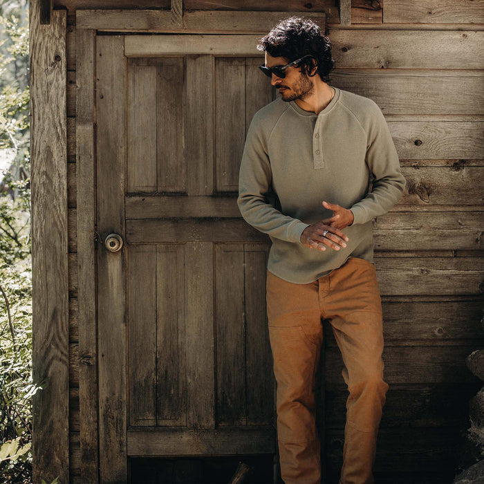 fit model leaning against the wall wearing The Heavy Bag Waffle Henley in Army