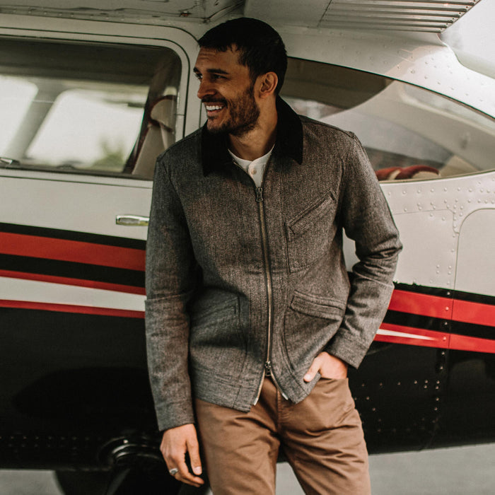 fit model wearing The Ignition Jacket in Indigo Salt and Pepper in front of a plane