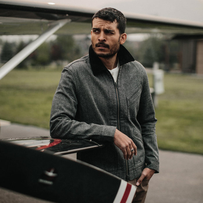 fit model wearing The Ignition Jacket in Indigo Salt and Pepper leaning against plane