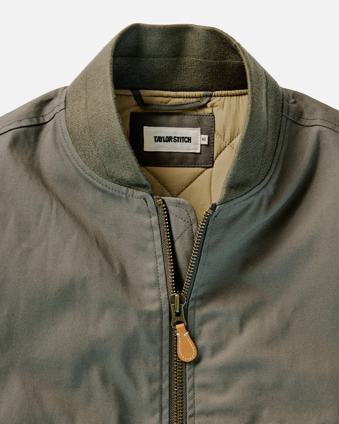 fit model leaning against a wall in The Insulated Bomber Jacket in Fatigue Olive Dry Wax