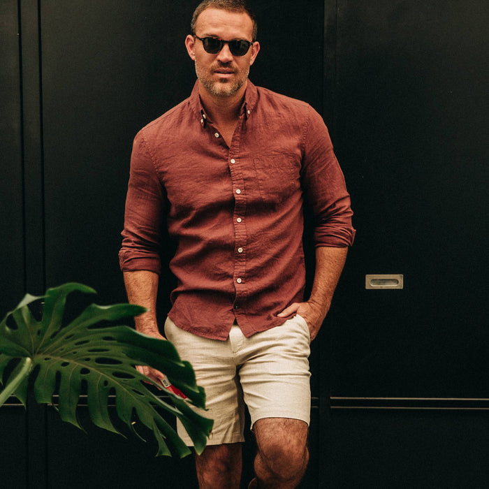 fit model wearing The Jack in Rust Linen, looking at camera, next to plant