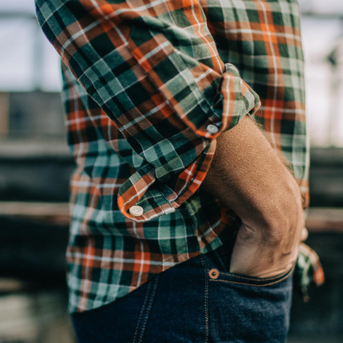 Fit model with sleeves rolled up and hands in pocket of The Jack in Rust Plaid Oxford