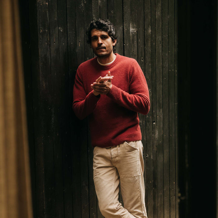 fit model leaning against the wall wearing The Lodge Sweater in Bonfire Donegal