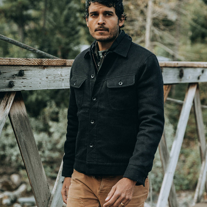 fit model wearing The Long Haul Jacket in Black Indigo Sashiko—walking on bridge