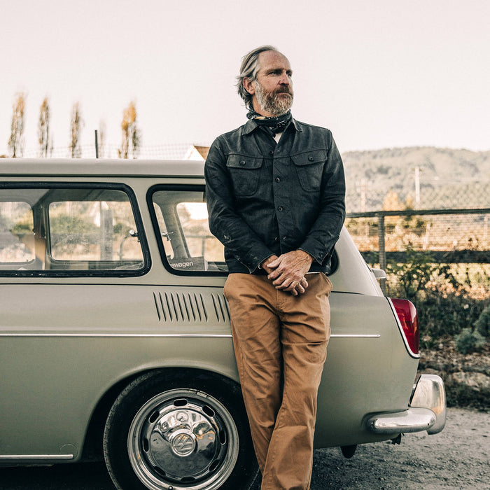 fit model wearing The Long Haul Jacket in Black Over-dye Selvage, leaning against car