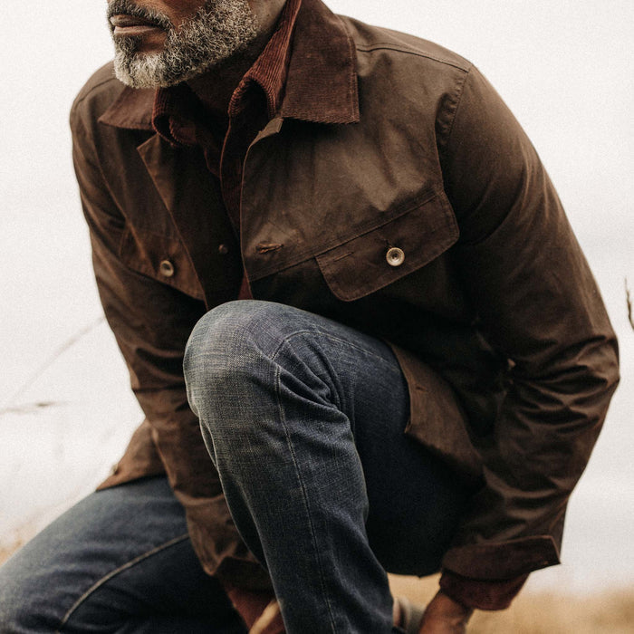fit model crouching wearing The Long Haul Jacket in Dark Khaki Waxed Canvas