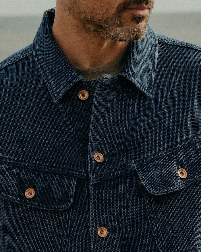 close up of the front pockets and antique copper buttons on The Long Haul Jacket in Rinsed Indigo Waffle