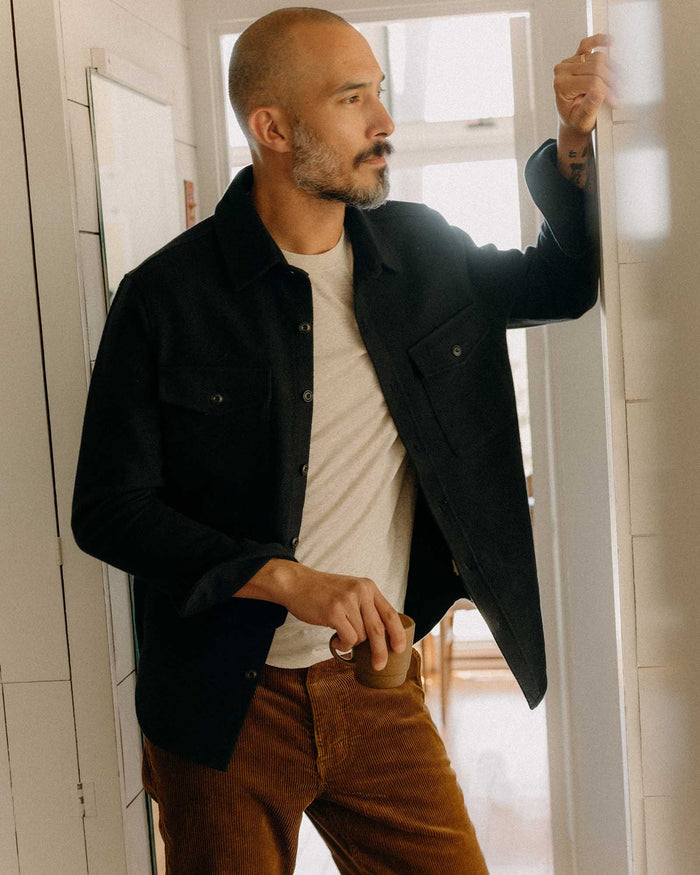 fit model leaning against the wall wearing The Maritime Shirt Jacket in Dark Navy Moleskin Twill
