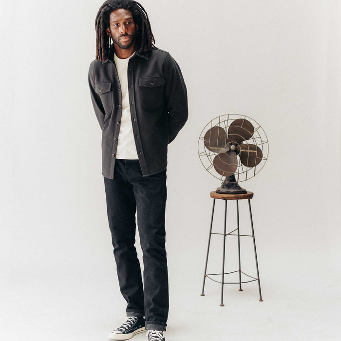fit model posing next to a fan wearing The Maritime Shirt Jacket in Faded Black Moleskin Twill