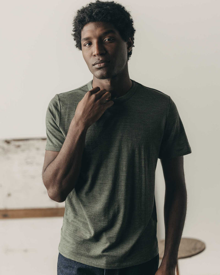 fit model leaning against the wall wearing The Merino Tee in Heather Army