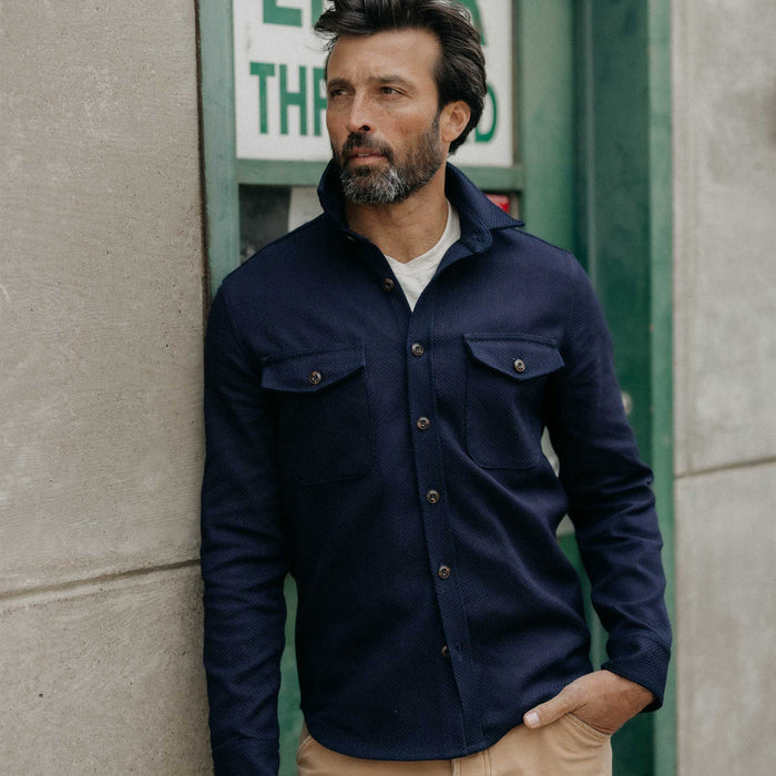 fit model leaning against the wall wearing The Mill Shirt Jacket in Rigid Indigo Sashiko