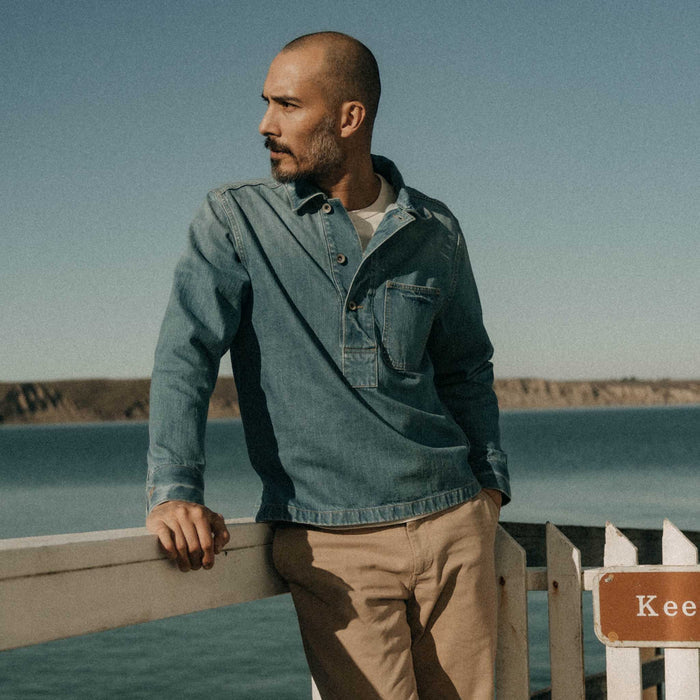 fit model leaning against the wall wearing The Milton Pullover in Washed Selvedge Denim