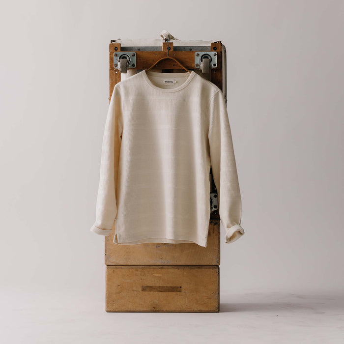 editorial image of The Morgan Crewneck in Natural Slub Stripe on a hanger on a trunk