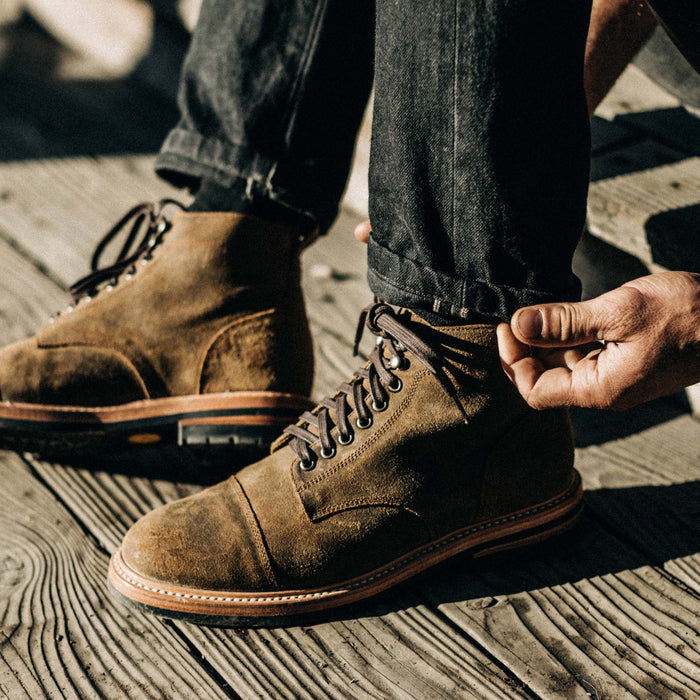 fit model cuffing his jeans while wearing The Moto Boot in Golden Brown Waxed Suede