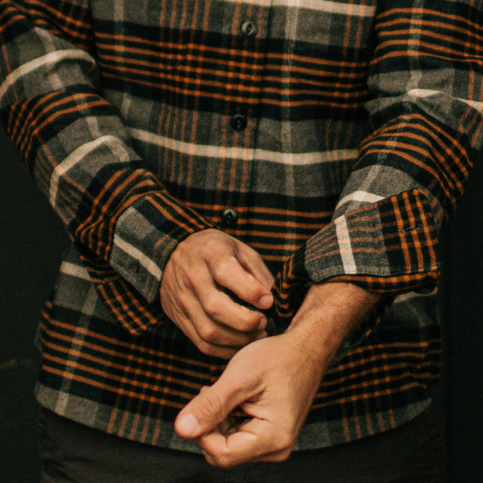 fit model rolling up sleeves of The Moto Shirt in Orange Plaid