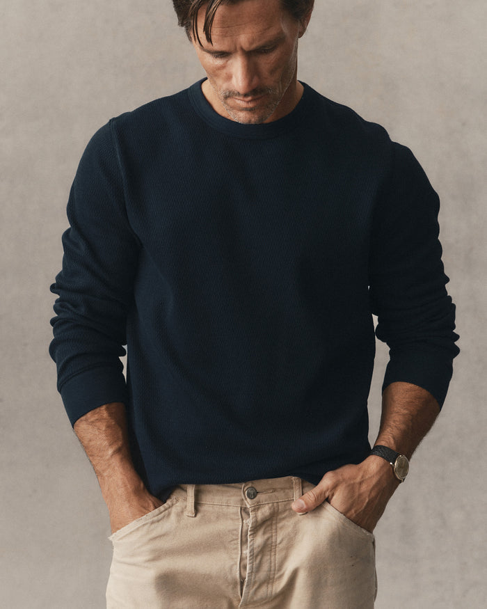 fit model leaning against a roof in The Organic Cotton Waffle Crew in Dark Navy