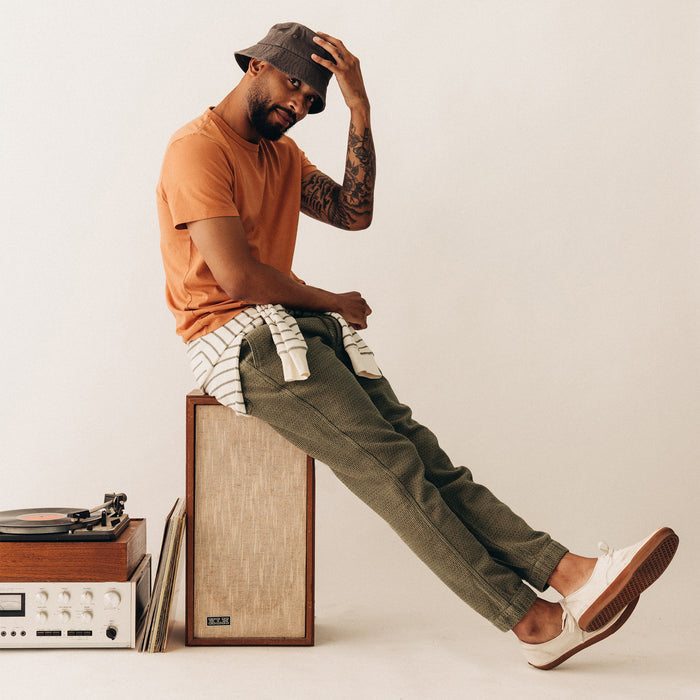 fit model sitting on a speaker wearing The Organic Cotton Tee in Adobe