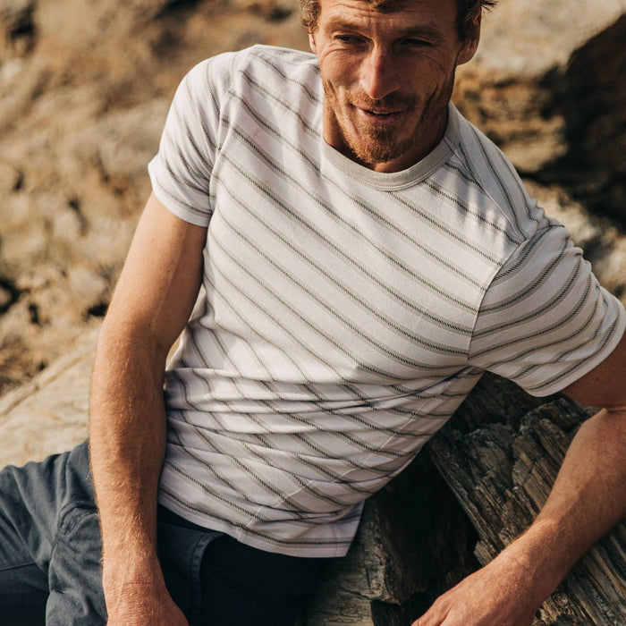 fit model wearing The Organic Cotton Tee in Graphite Stripe, cropped shot, sitting on rocks