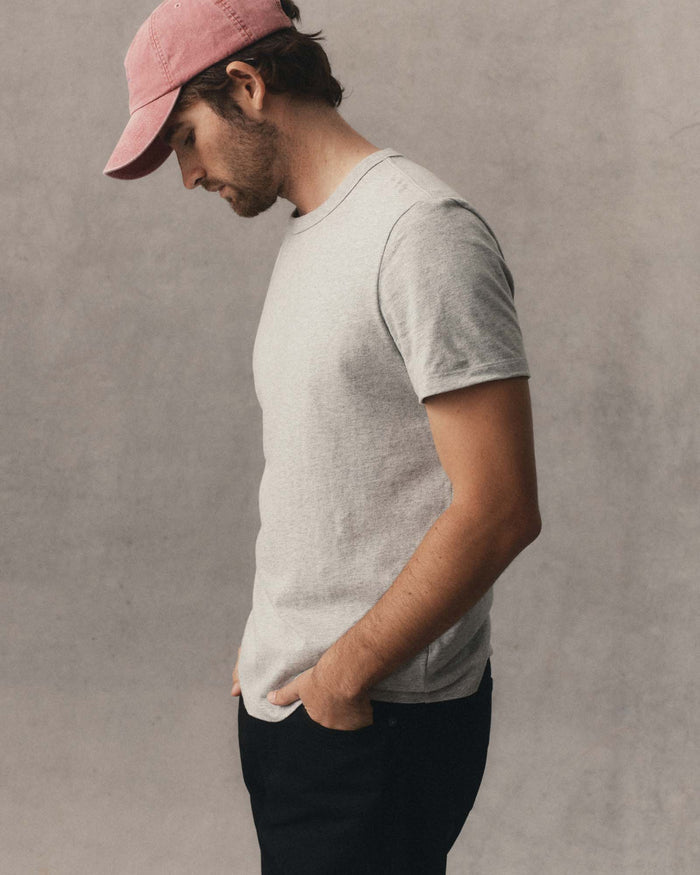 fit model sitting wearing The Organic Cotton Tee in Heather Grey