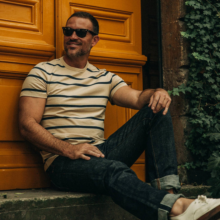 fit model wearing The Organic Cotton Tee in Khaki Stripe, sitting on ledge