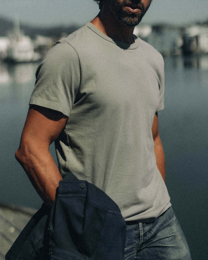 fit model sitting leaning against the wall in The Organic Cotton Tee in Sage
