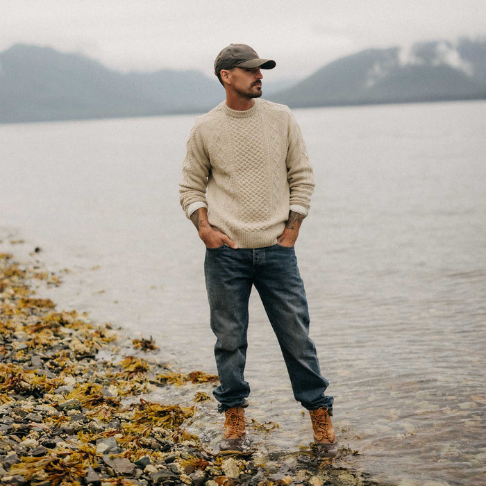 fit model standing in the water wearing The Orr Sweater in Marled Oat Merino