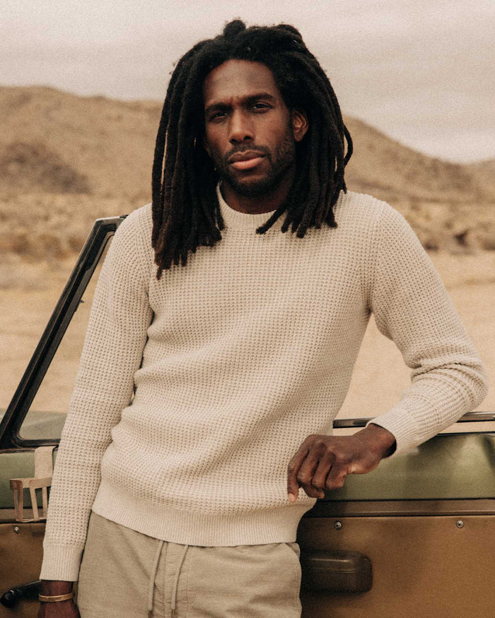 fit model leaning against a car wearing The Ranger Sweater in Heather Fog Linen Waffle