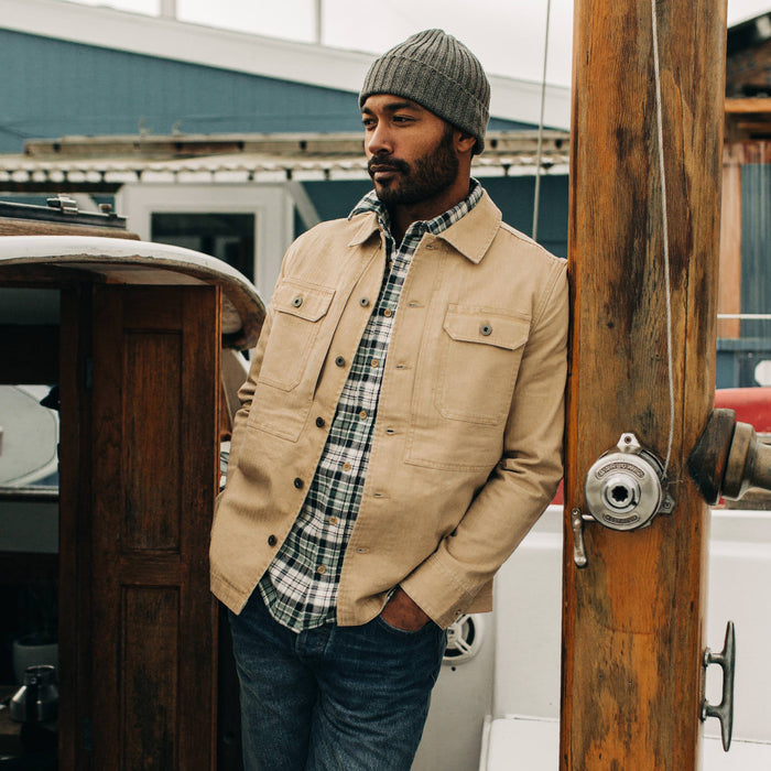 fit model leaning against piling wearing The Reserve Shirt in Khaki Herringbone