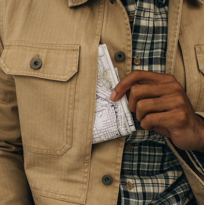 fit model wearing The Reserve Shirt in Khaki Herringbone pulling out a map from a pocket