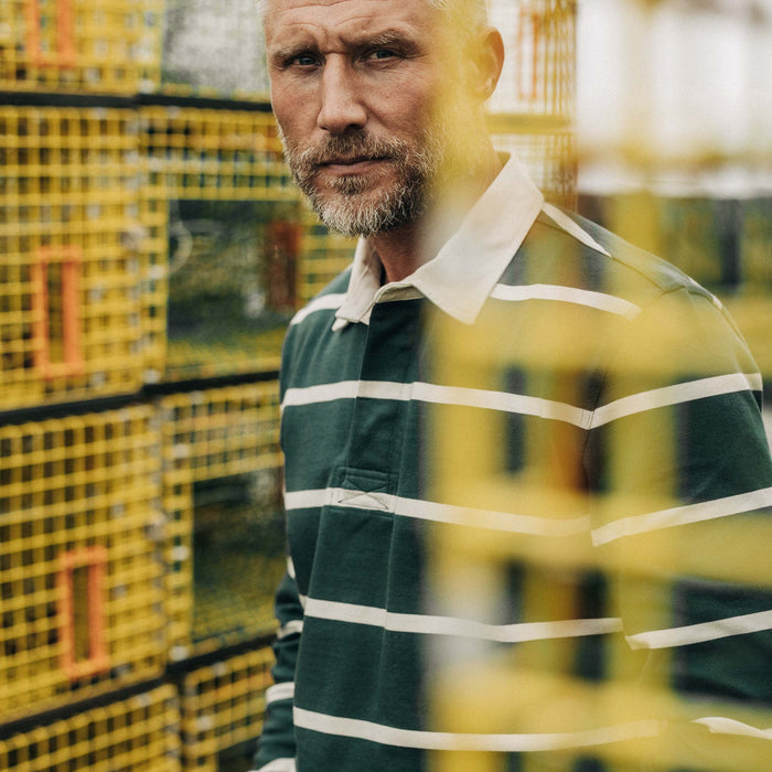 fit model looking through fishing boxes wearing The Rugby in Dark Forest Stripe