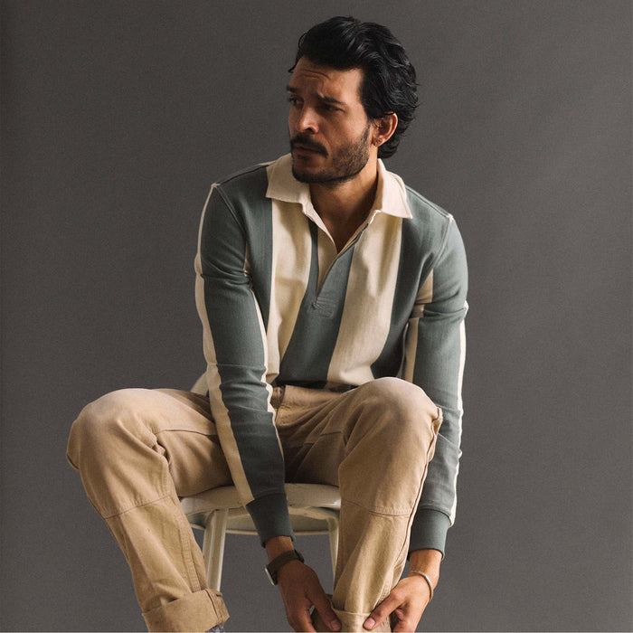 fit model adjusting his pant cuffs wearing The Rugby Shirt in Deep Sea Stripe