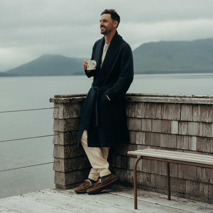 fit model leaning against the wall wearing The Shawl Robe in Heather Midnight Quilted Jersey