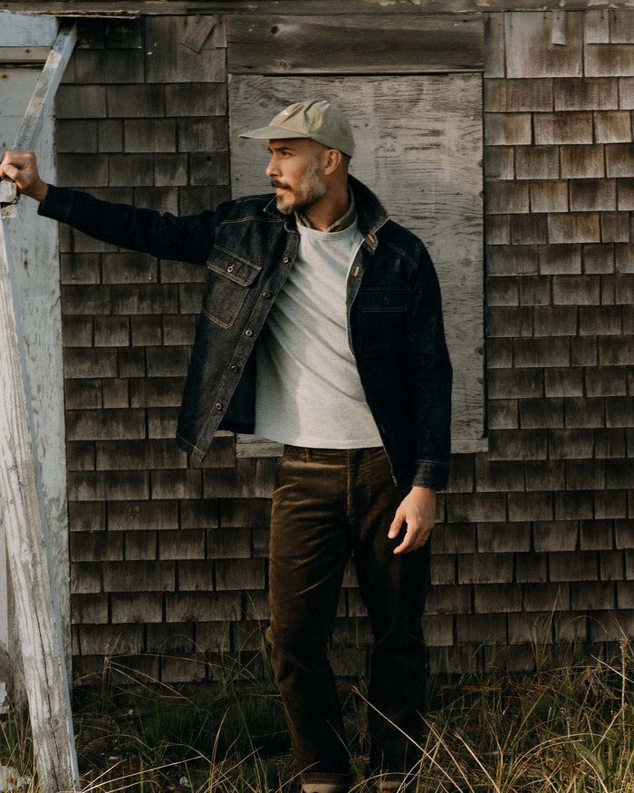 fit model leaning against the wall wearing The Shop Shirt in Rinsed Indigo Selvedge