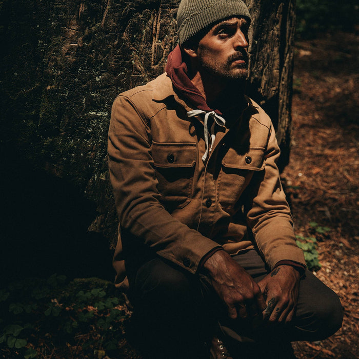 fit model wearing The Shop Shirt in Tobacco Boss Duck, sitting against tree
