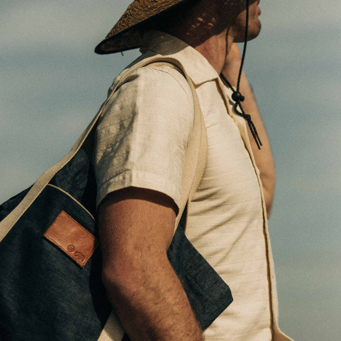 fit model wearing The Short Sleeve Hawthorne in Sand while holding a tote bag