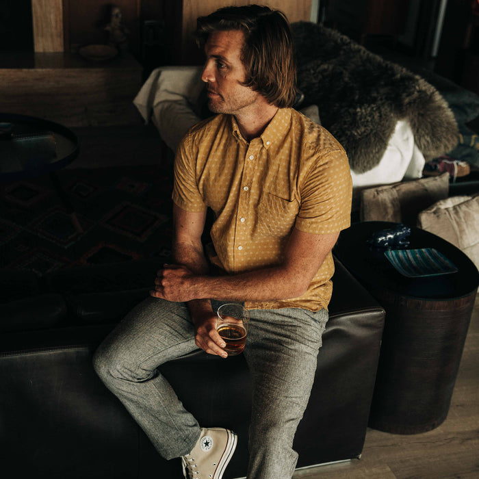 fit model sitting on a couch in The Short Sleeve Jack in Gold Diamond