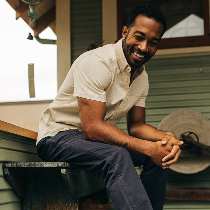 fit model wearing The Short Sleeve Jack in Natural Seersucker while sitting on a bench