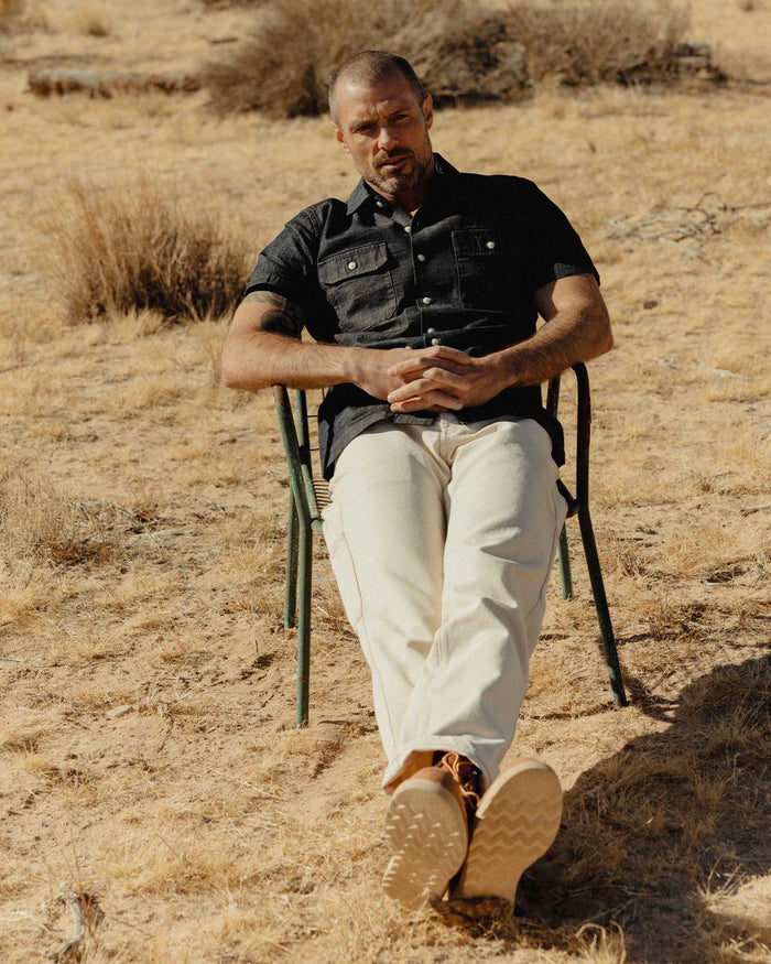 fit model sitting wearing The Short Sleeve Mechanic Shirt in Rinsed Indigo Denim
