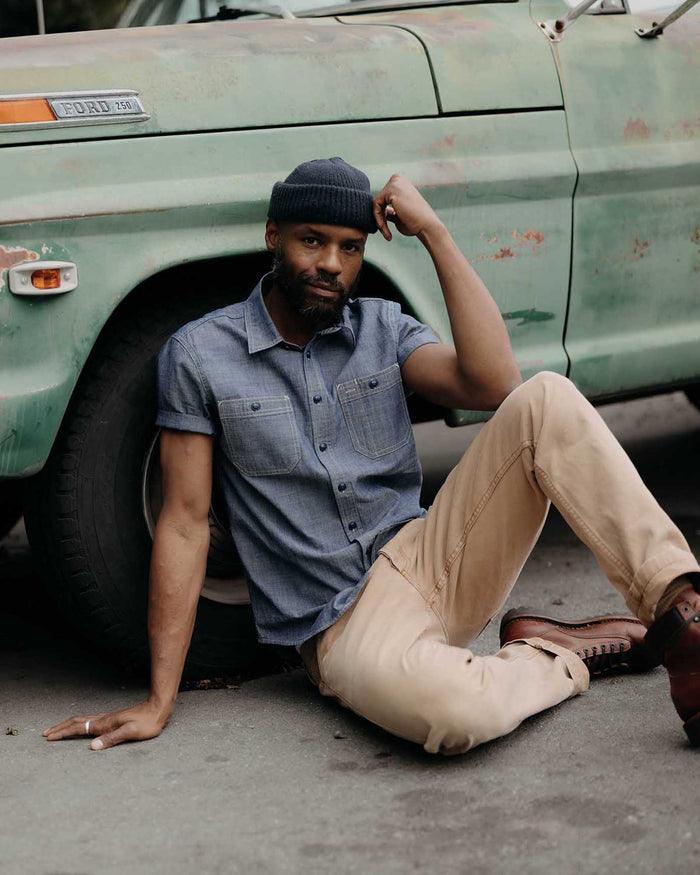 fit model sitting wearing The Short Sleeve Utility Shirt in Indigo Selvedge Chambray