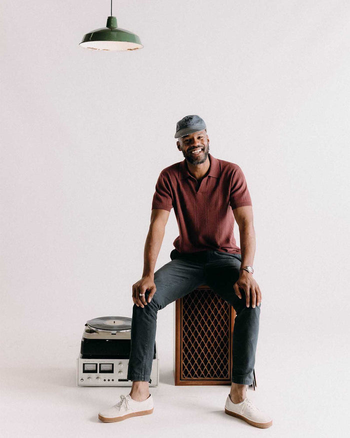 fit model sitting on a speaker wearing The Slim Foundation Pant in Organic Navy