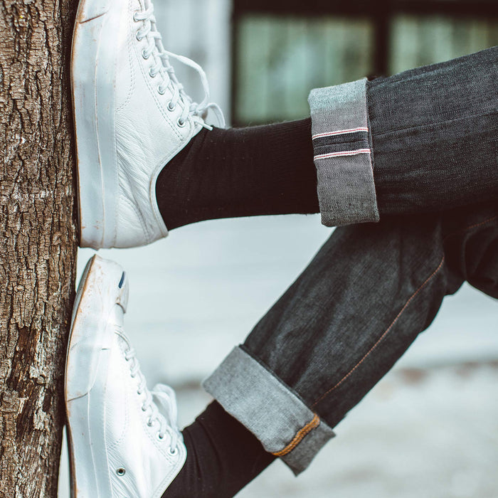 Fit model with cuffed denim and white shoes