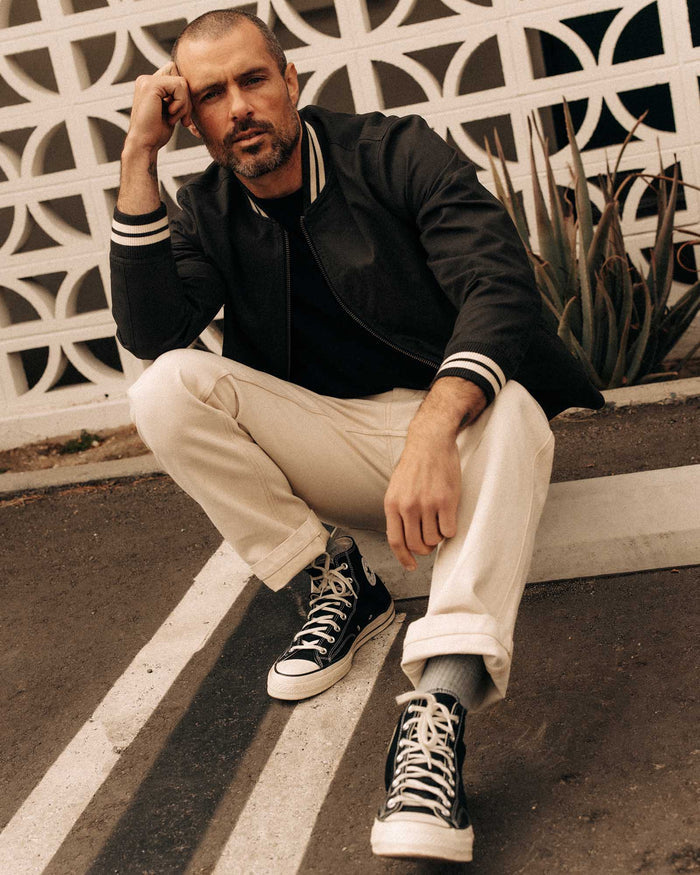 fit model sitting wearing The Speedway Bomber in Organic Faded Black Twill