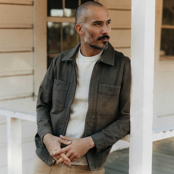 fit model leaning against a pole wearing The Station Jacket in Fatigue Olive Broken Twill