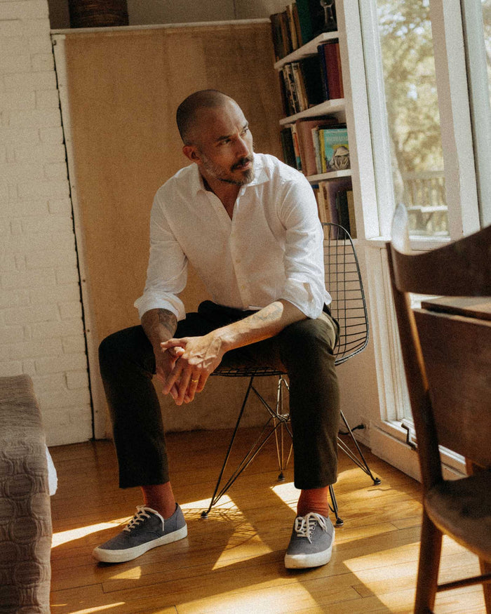 fit model sitting wearing The Stevens Trouser in Black Olive Wool Flannel