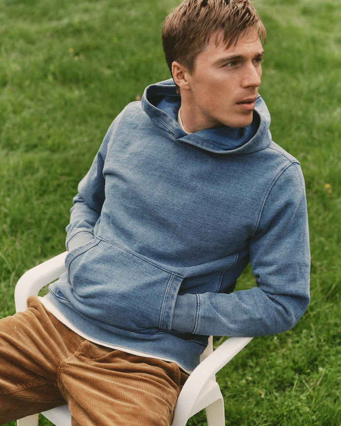 fit model sitting wearing The Apres Hoodie in Washed Indigo Terry