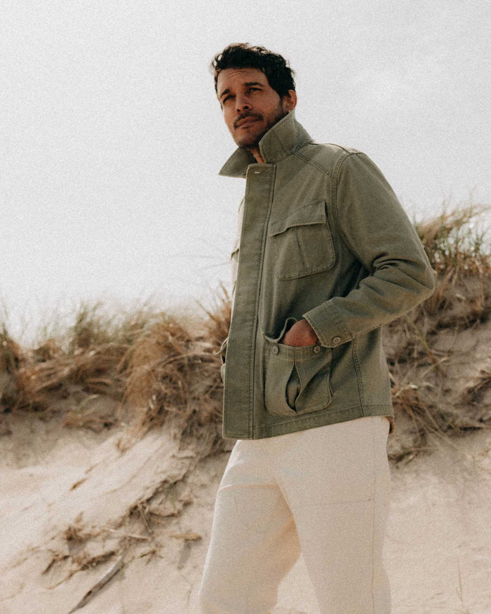 fit model with his hands in his pockets wearing The Surplus Jacket in Field Olive Reverse Sateen