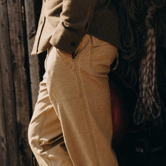 fit model leaning against the wall wearing The Surplus Pant in Khaki Reverse Sateen
