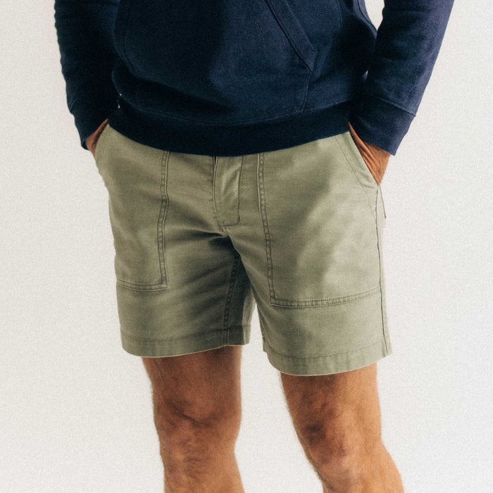 fit model with his hands in his pockets wearing The Surplus Short in Field Olive Reverse Sateen