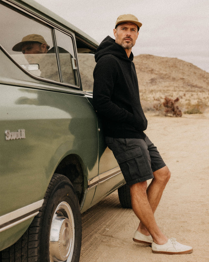 fit model leaning against a car wearing The Tommie Short in Faded Black Broken Twill